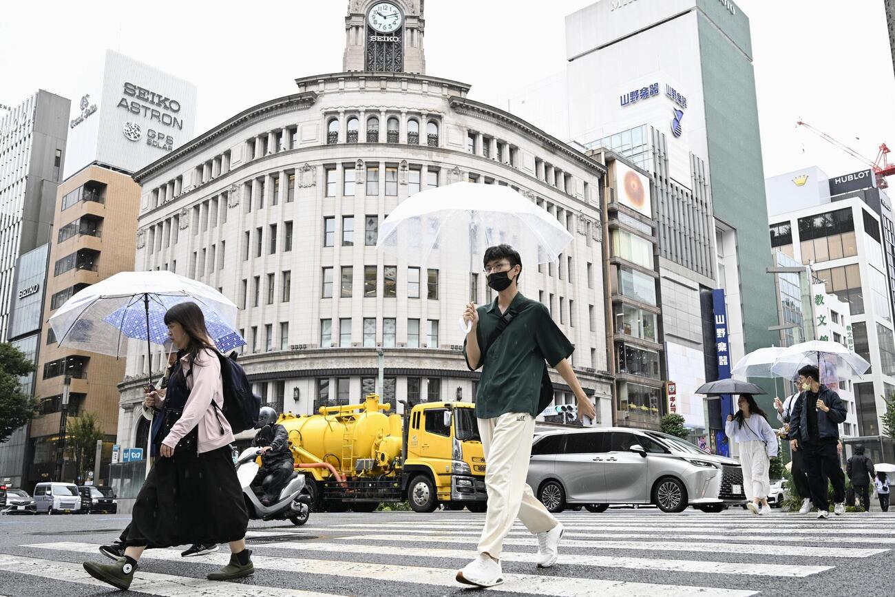 東京・銀座を傘を差して歩く人たち。都心で連続降雨過去最長を記録した（共同）