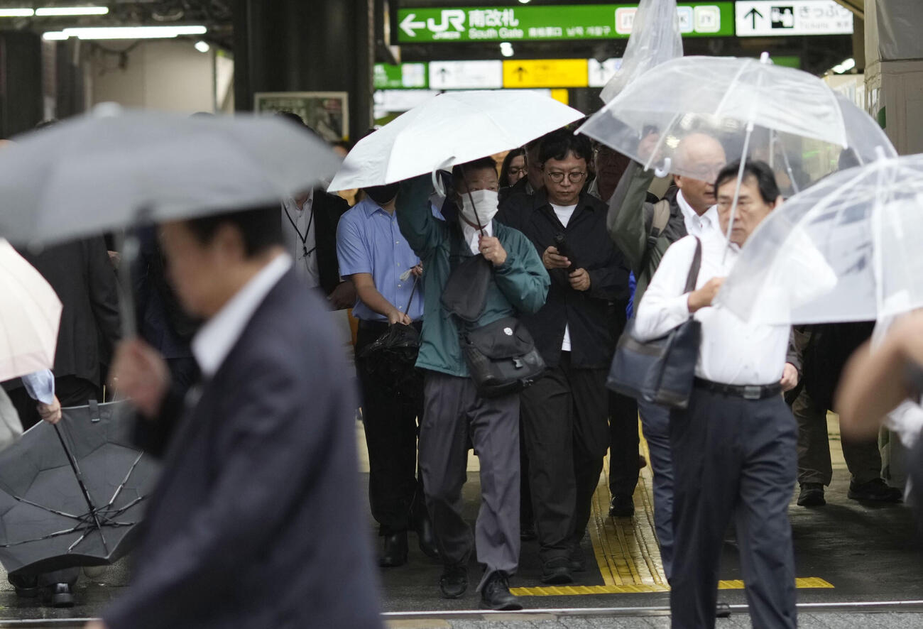 傘を差して東京・新橋駅前を歩く人たち。都心の雨は35日連続となり、最長記録をさらに更新した＝9月30日（共同）