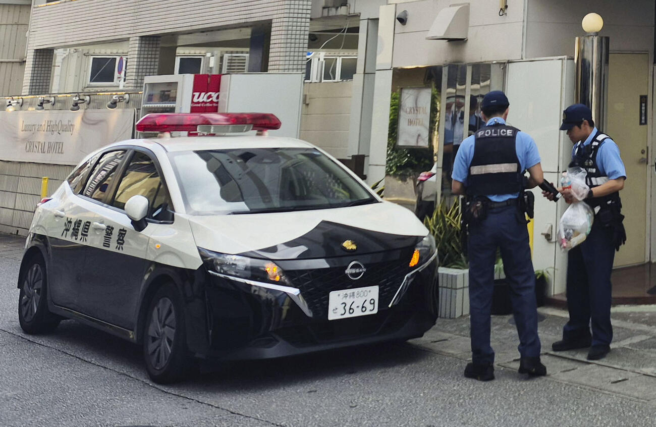 女性の遺体が見つかった現場周辺で捜査を続ける警察官ら＝4日午前、那覇市（共同）