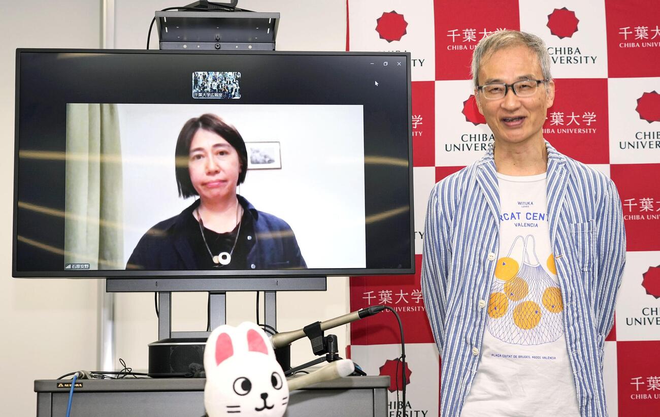 「アイスキューブ」の米研究者がノーベル物理学賞に決まり、記者会見で笑顔を見せる千葉大の吉田滋教授。左の画面は石原安野教授＝6日午後8時35分、千葉市(共同)