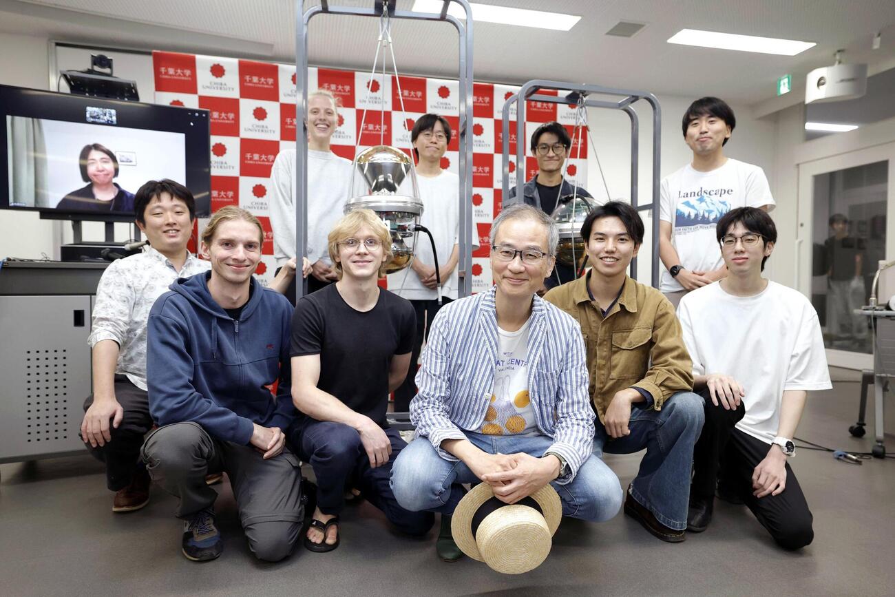 記者会見を終え、学生らと笑顔を見せる千葉大の吉田滋教授（手前中央）。左奥の画面は石原安野教授＝6日午後9時54分、千葉市(共同)