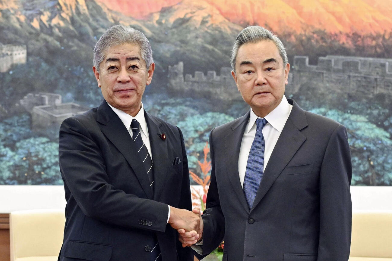 中国の王毅外相（右）と握手する岩屋毅前外相＝9月、北京（新華社＝共同）