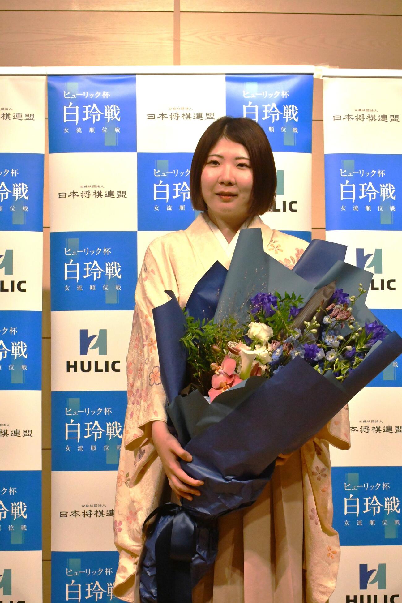 防衛を果たして花束を手にする西山朋佳白玲