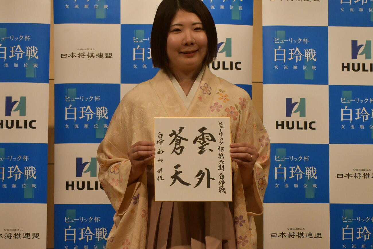 防衛とクイーン白玲獲得の記念に揮毫（きごう）した色紙を見せる西山朋佳白玲
