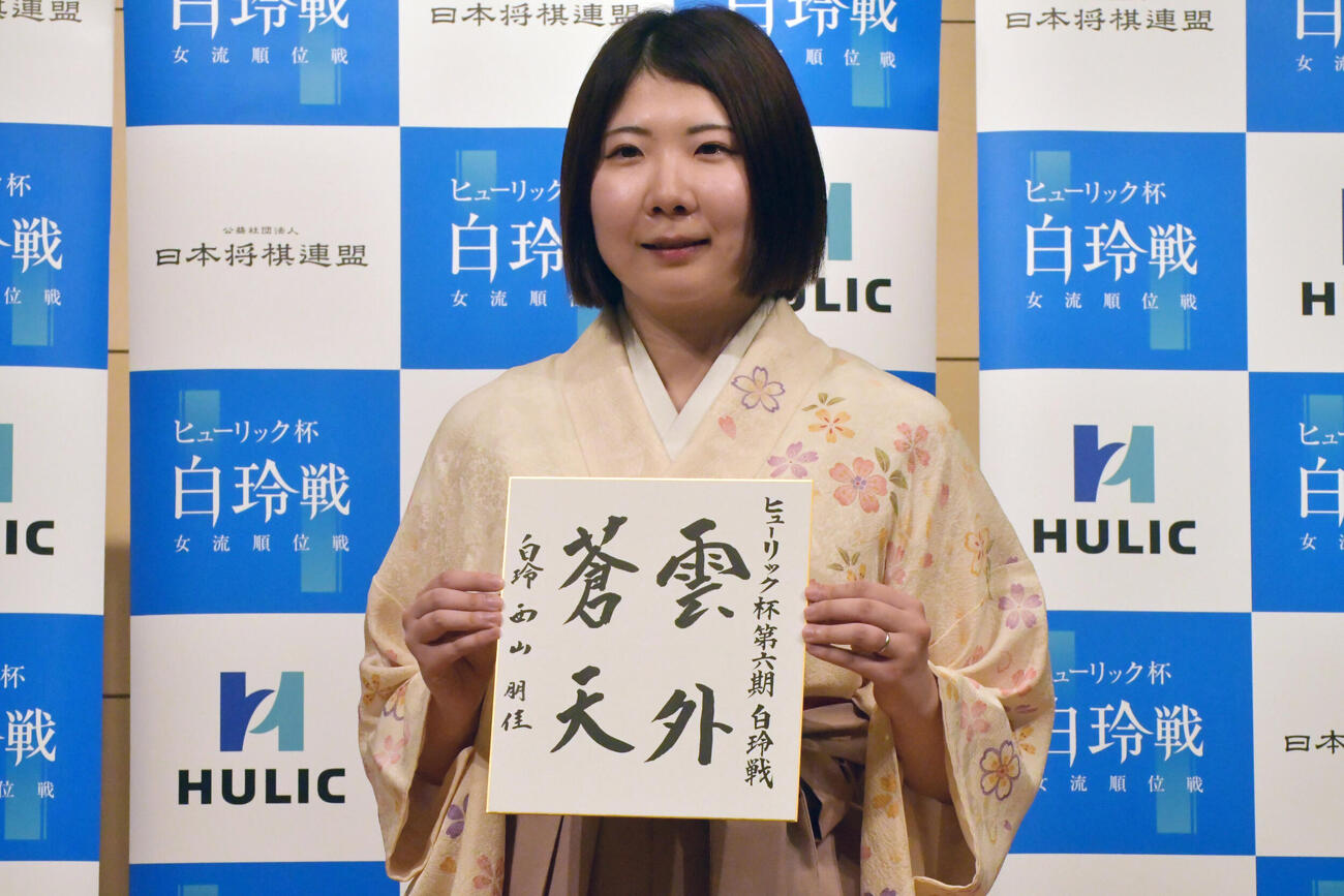 防衛とクイーン白玲獲得の記念に揮毫（きごう）した色紙を見せる西山朋佳白玲