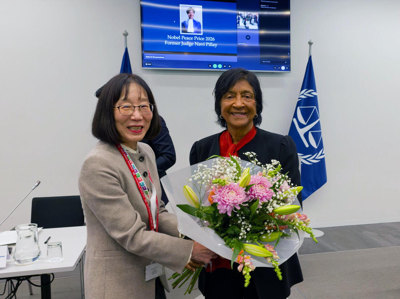 国際刑事裁判所（ICC）を訪問し、赤根智子所長（左）から花束を贈られるピレイ元国連人権高等弁務官＝12日、オランダ西部ハーグ（ICC提供・共同）