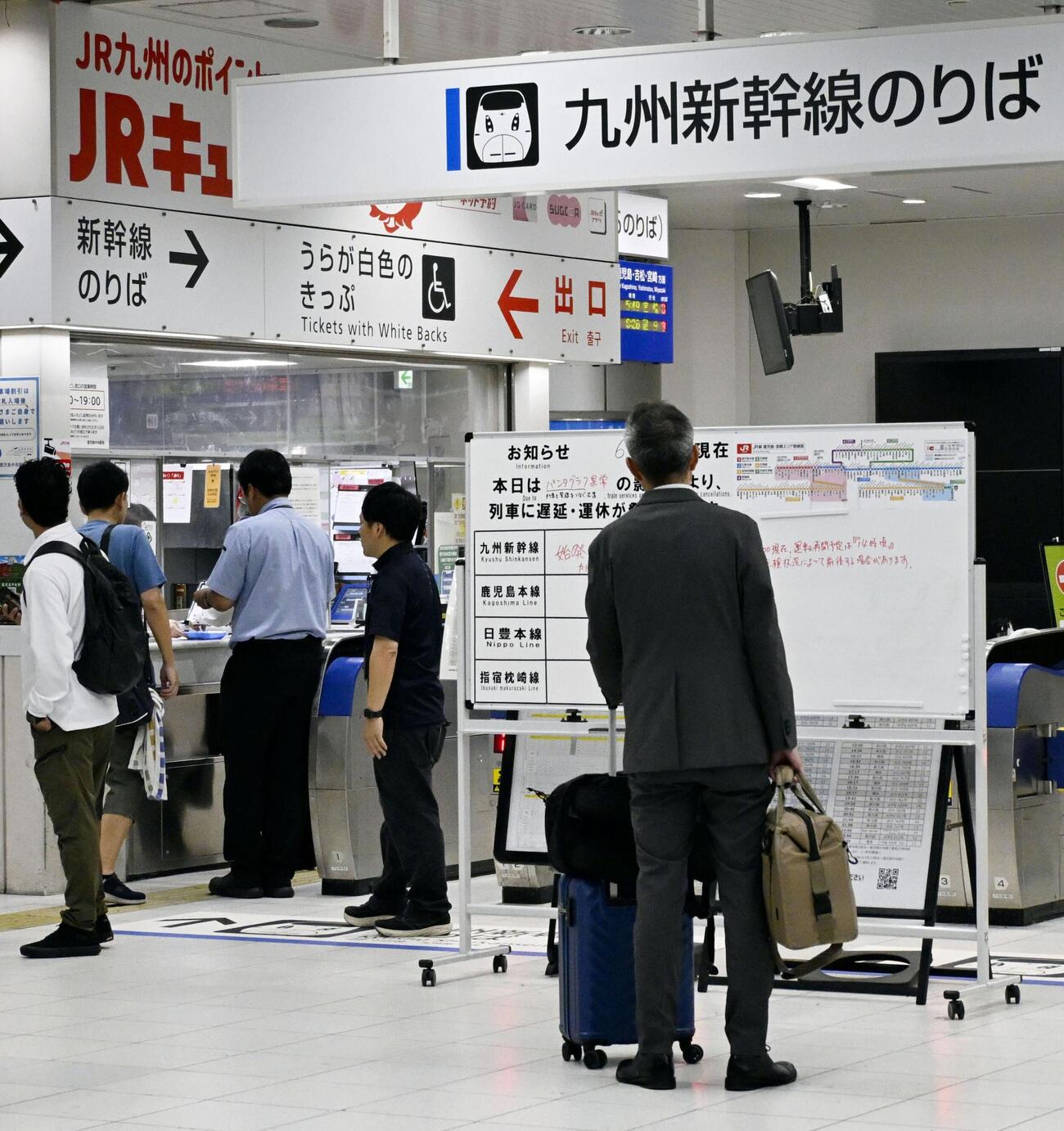 九州新幹線の運転見合わせで、掲示板を見つめる利用客＝13日午前、JR鹿児島中央駅（共同）
