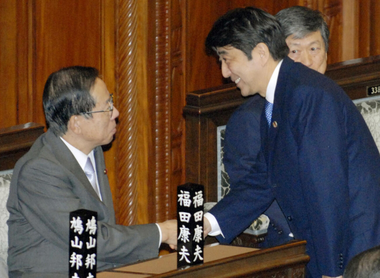 2007年11月、衆院本会議で新テロ対策特別措置法案の投票を終えた安倍晋三前首相（右）と握手する福田康夫首相(共同)