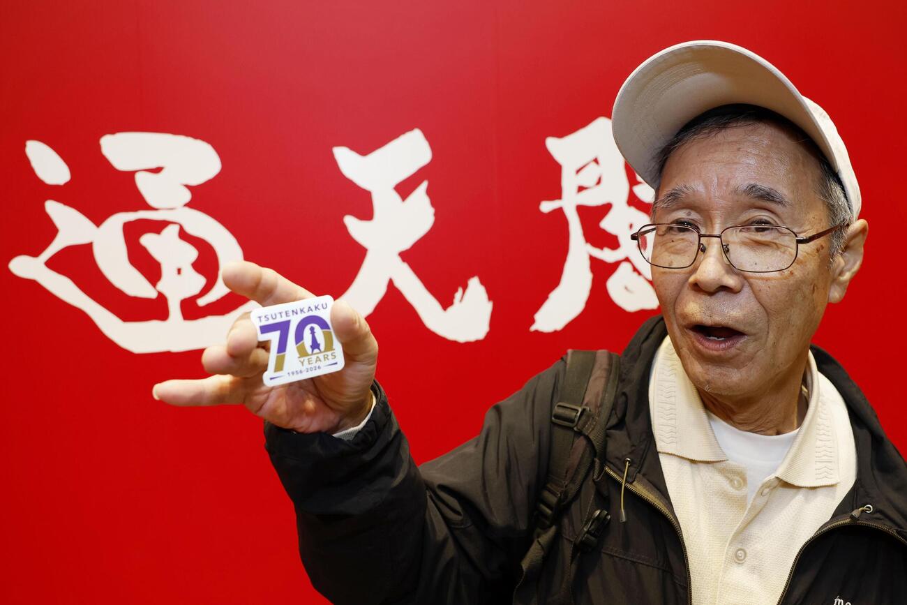 開業70周年を記念して配られた「通天閣」のマグネットシートを手にする西村和彦さん（共同）