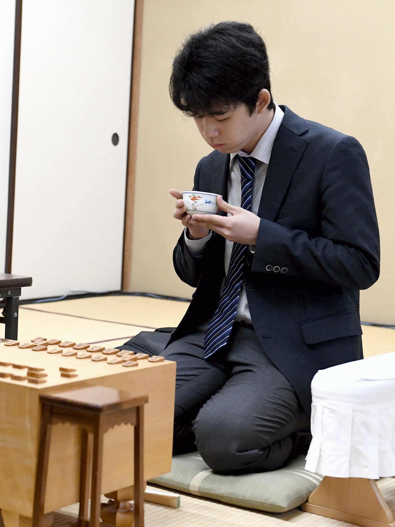 藤井四段は手にした茶に息を吹き掛けて冷ます（撮影・山崎安昭）