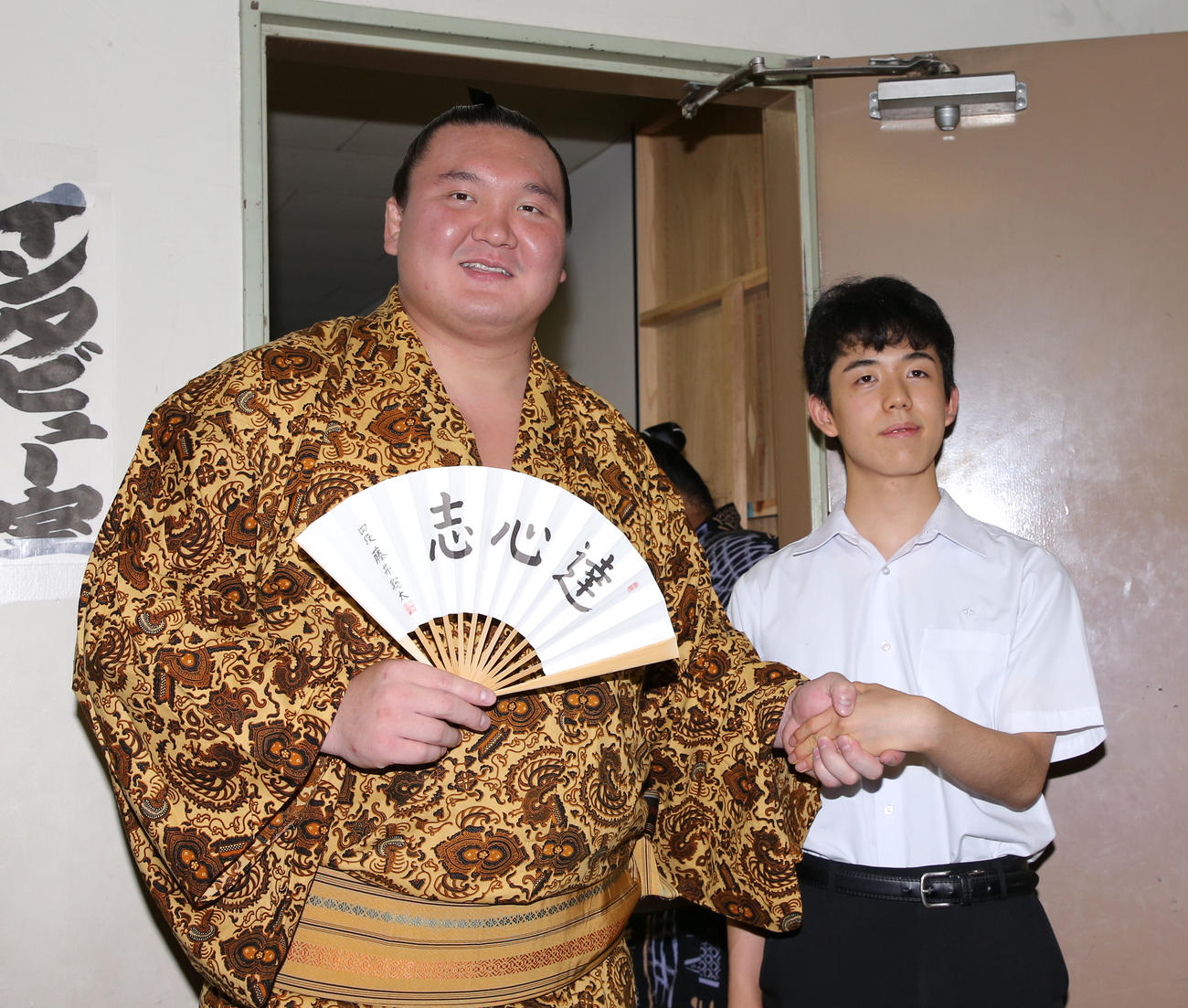藤井四段（右）は支度部屋を訪れ、直筆の扇子をプレゼントした白鵬と握手（撮影・加藤哉）