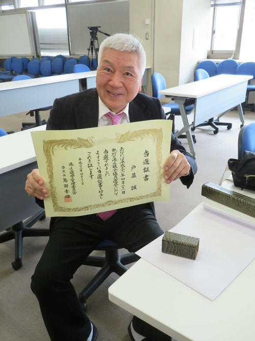 港区議会議員選挙で初当選し、当選証書を手にスマイルを披露するマック赤坂氏（撮影・村上幸将）
