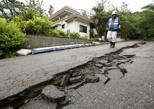 亀裂が入った道路。ブロック塀も崩れていた＝19日午前8時47分、山形県鶴岡市（共同）