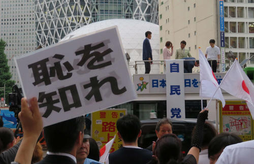 新宿駅西口の自民党街頭演説会を終え、退場する三原じゅん子氏に向かって「恥を知れ」と書かれたボードを掲げる聴衆（撮影・村上幸将）