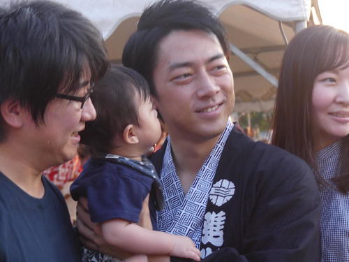 地元の夏祭り会場で、赤ちゃんを抱いて写真撮影に応じる小泉進次郎氏