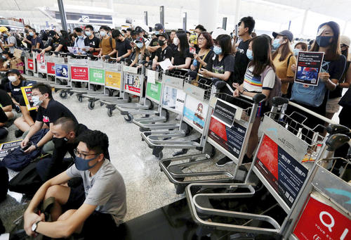 「逃亡犯条例」改正案を巡り、香港国際空港でカートを使いバリケードを作るデモ隊＝13日（ロイター）