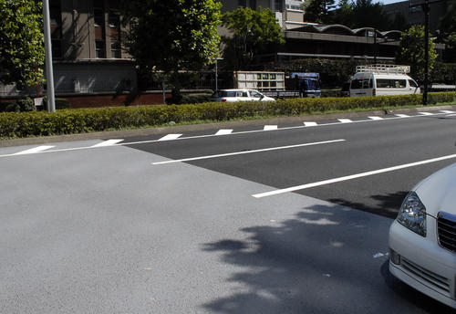 遮熱舗装（左）と排水舗装（右）の境目。遮熱舗装は他の舗装より明るい灰色に見える（15年8月撮影）