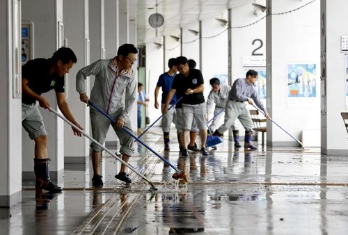 大雨で浸水したJR佐賀駅で、水をかき出す人たち（共同）
