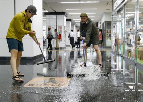 大雨で浸水したJR佐賀駅で、水をかき出す近隣の住民ら（共同）