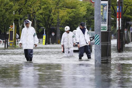 大雨で冠水した道路を見回る警察官（共同）