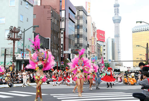浅草サンバカーニバルで盛り上がるダンサー。右後方は東京スカイツリー（撮影・鹿野芳博）
