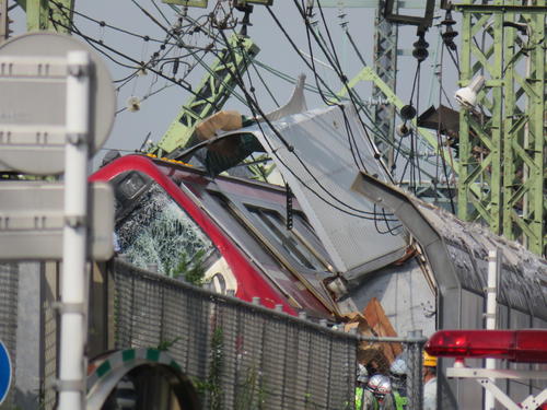 京浜急行の神奈川新町－仲木戸間の踏切で、トラックと衝突し脱線した車両を前に、パトカーや報道陣が集まり騒然とした事故現場（撮影・村上幸将）