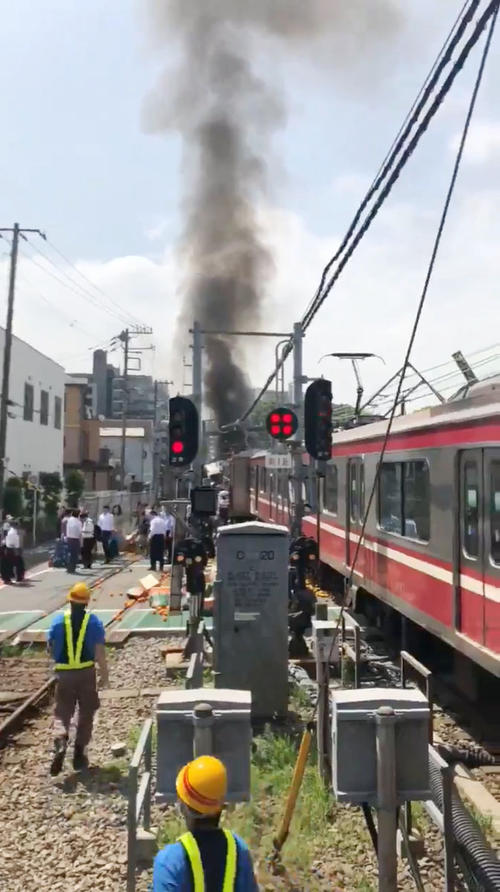 京浜急行の電車とトラックが衝突し、黒煙が上がる事故現場（共同）