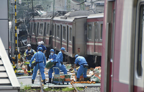 京浜急行の車両がトラックと衝突した踏切付近で、散乱したものを片付ける神奈川県警の捜査員ら（共同）