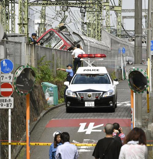 京浜急行の車両がトラックと衝突した事故現場を遠巻きにする人たち（共同）