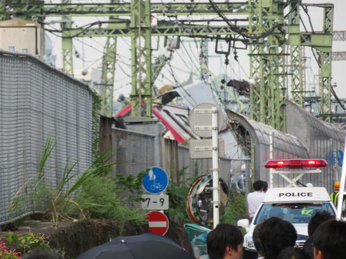 京浜急行の神奈川新町－仲木戸間の踏切で、トラックと衝突し脱線した車両を前に、パトカーや報道陣が集まり騒然とした事故現場（撮影・村上幸将）