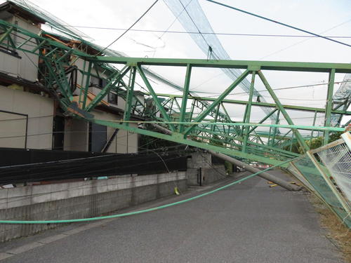 台風15号の影響で、ゴルフ練習場「市原ゴルフガーデン」のネットを支えていた鉄製の支柱が隣接の住宅に倒れ込み、車も通れない状態が続いている（撮影・近藤由美子）