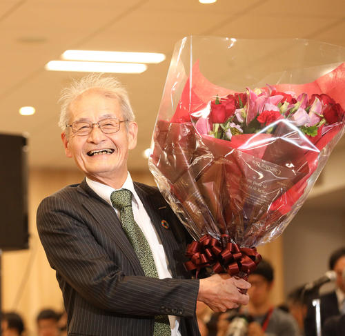 会見場で祝福される中、花束を抱え満面の笑顔を見せるノーベル化学賞受賞を決めた旭化成名誉フェローの吉野彰氏（撮影・河田真司）