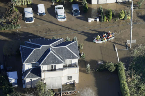 13日午前7時5分、埼玉県坂戸市　台風19号の大雨で冠水した市街地をボートで進む救急隊員ら（共同）