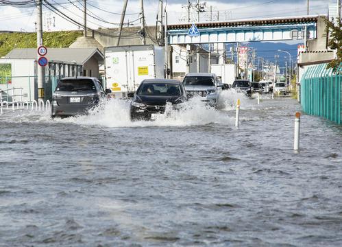 13日午前8時29分、宮城県柴田町　冠水し川のようになった道路を進む車（共同）