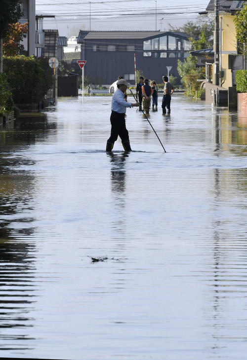 13日午後3時17分　台風19号の影響で冠水した道路を歩く人（共同）