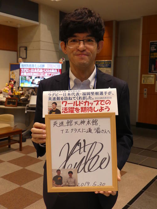 今年5月、福岡が来校した際に在校生へ残したサインを手にする担当の神田岳彦さん