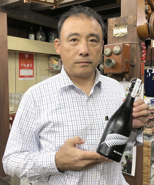 純米大吟醸「ALL　BLACKS　Junmai　Daiginjo」を手にする片山貴之さん