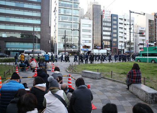 青山一丁目付近の待機列の前を大勢の警官が配置に向かう＝10日、6時30分（撮影・河野匠）