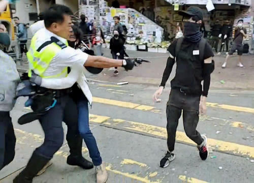11日、香港で抗議活動中の若者（右）に実弾を発砲する警官（香港メディア「丘品新聞」提供・共同）