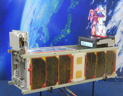 初公開された超小型衛星と、搭載される「ガンダム」と「シャアザク」の模型（撮影・大上悟）