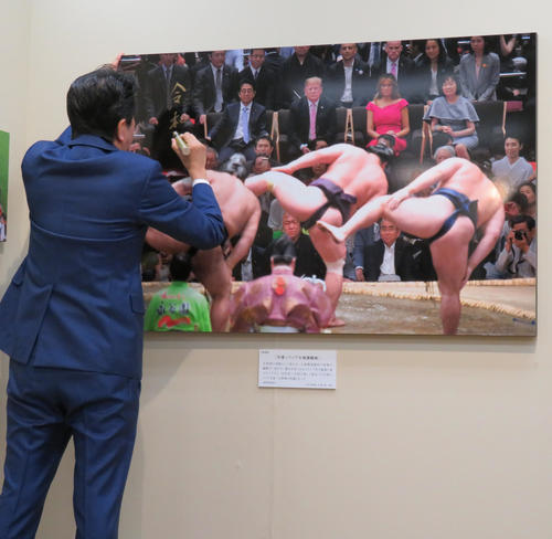 報道写真展の視察に訪れた安倍首相はサインを書く（撮影・佐藤勝亮）