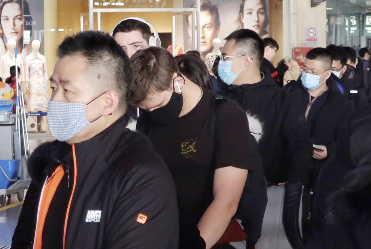 21日、北京国際空港でマスクをして並ぶ人たち（共同）