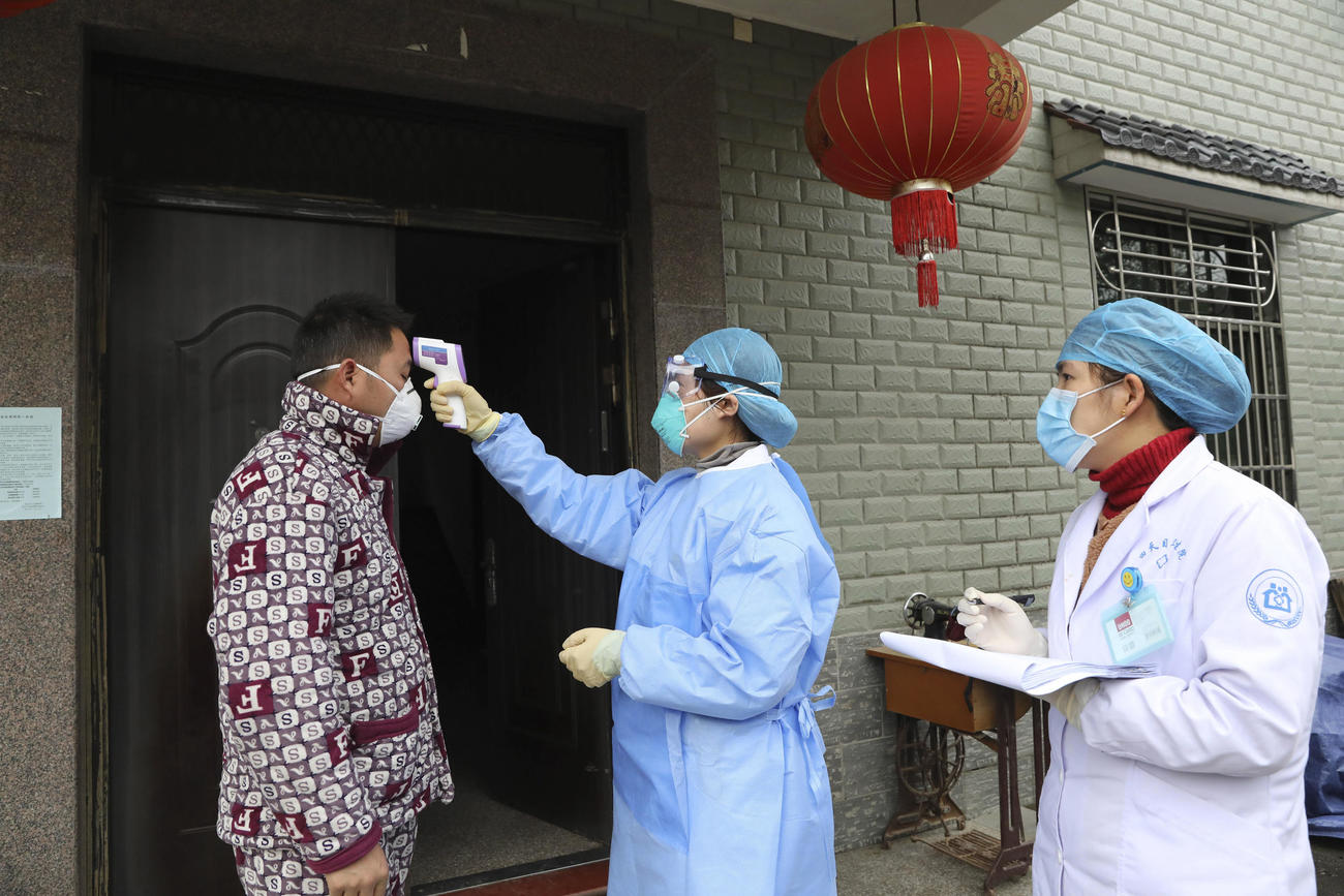 杭州市で、湖北省から戻った人の体温を計測する保健関係職員（AP）