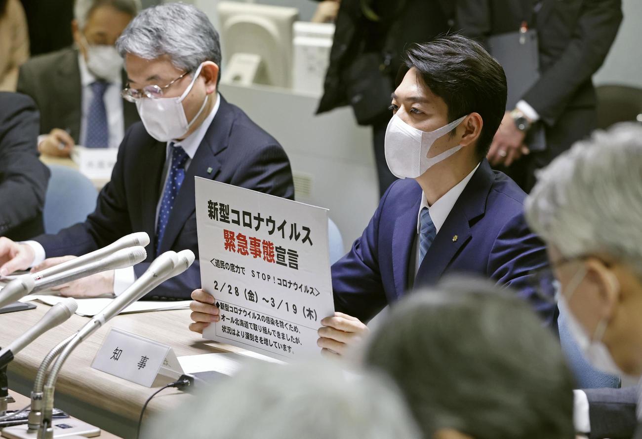 新型コロナウイルスの感染拡大を受け、「緊急事態宣言」を出す北海道の鈴木直道知事（右）（共同）