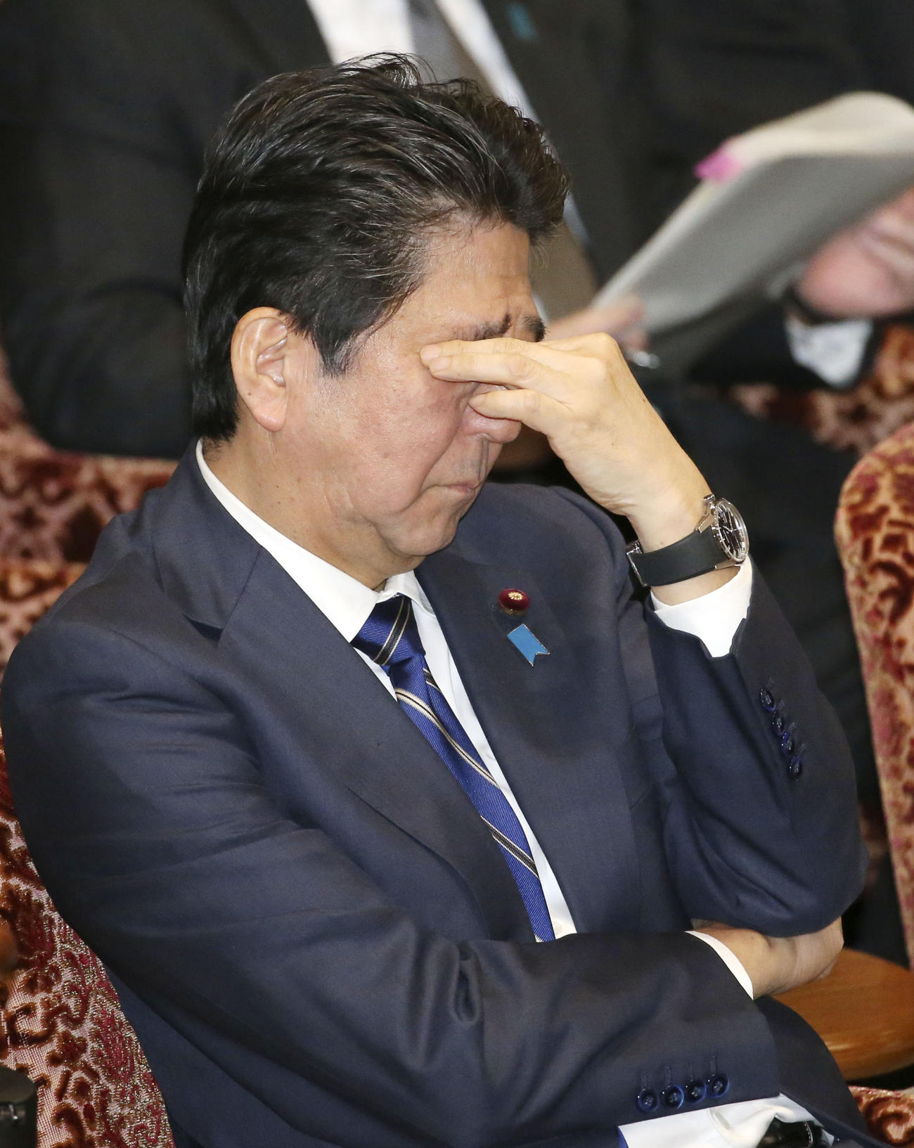 参院予算委でまぶたを押さえながら質問を聞く安倍首相（共同）