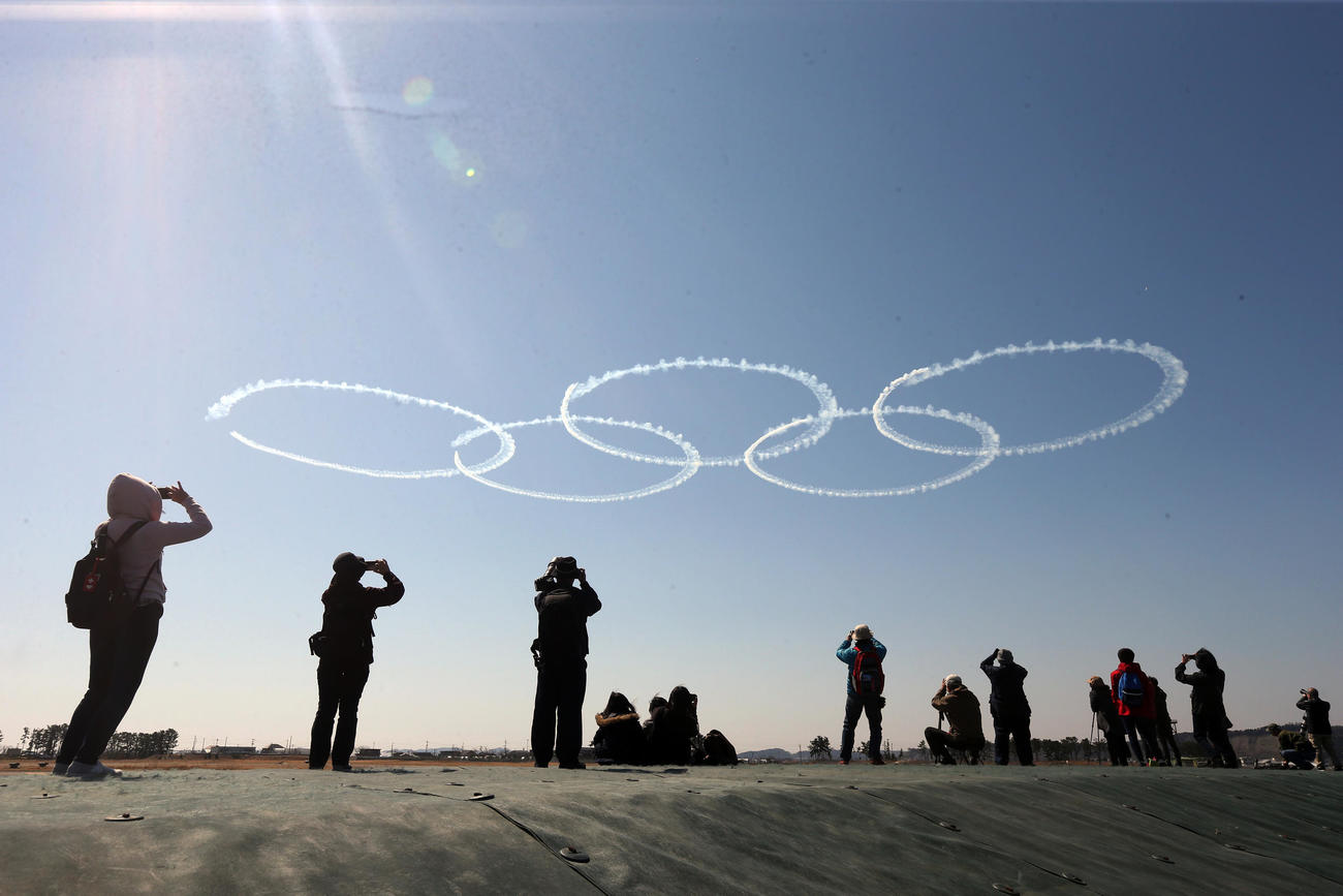 20日の東京五輪聖火到着式を前に、展示飛行の訓練を行う航空自衛隊松島基地のブルーインパルス。多くの人が集まる中、青空にスモークで五輪マークが描かれた（撮影・野上伸悟）