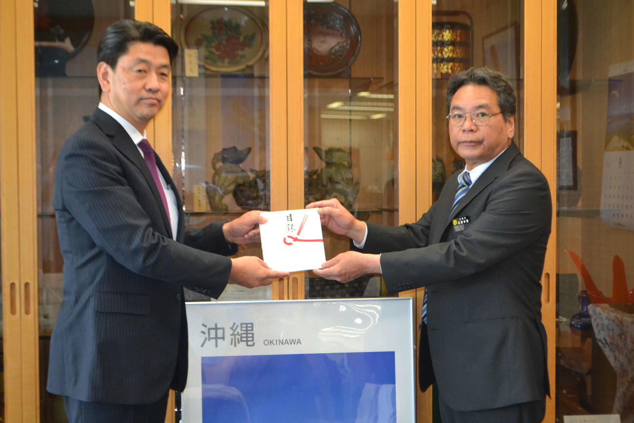 首里城復興支援のために集めた募金の目録を沖縄県東京事務所の石垣永浩副所長（右）に手渡す小田原市の加藤憲一市長（左）
