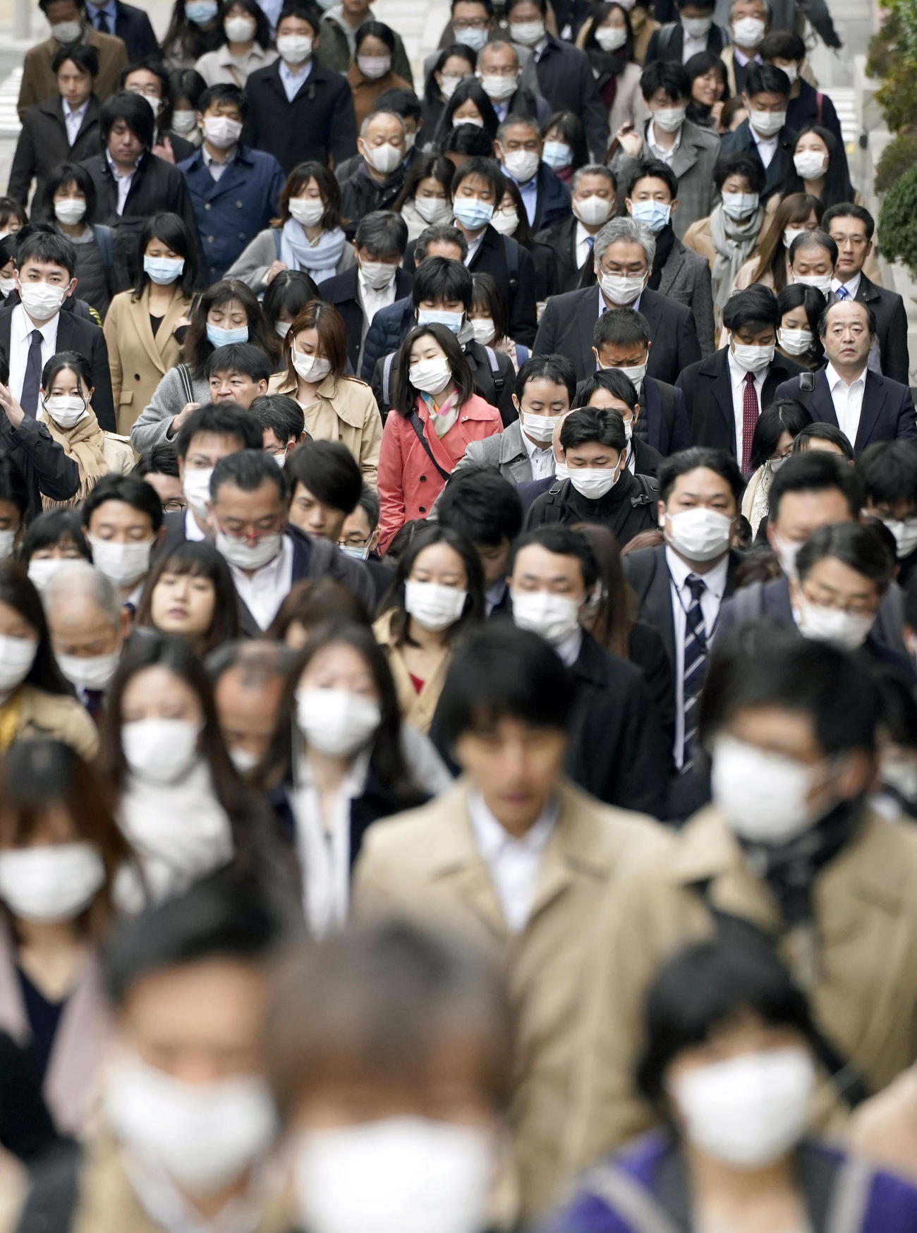 東京都内でマスクを着けて通勤する人たち（共同）