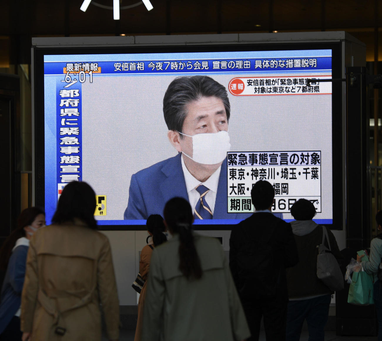 安倍首相の緊急事態宣言発令を伝えるニュースを足を止めてみる人々（撮影・前岡正明）