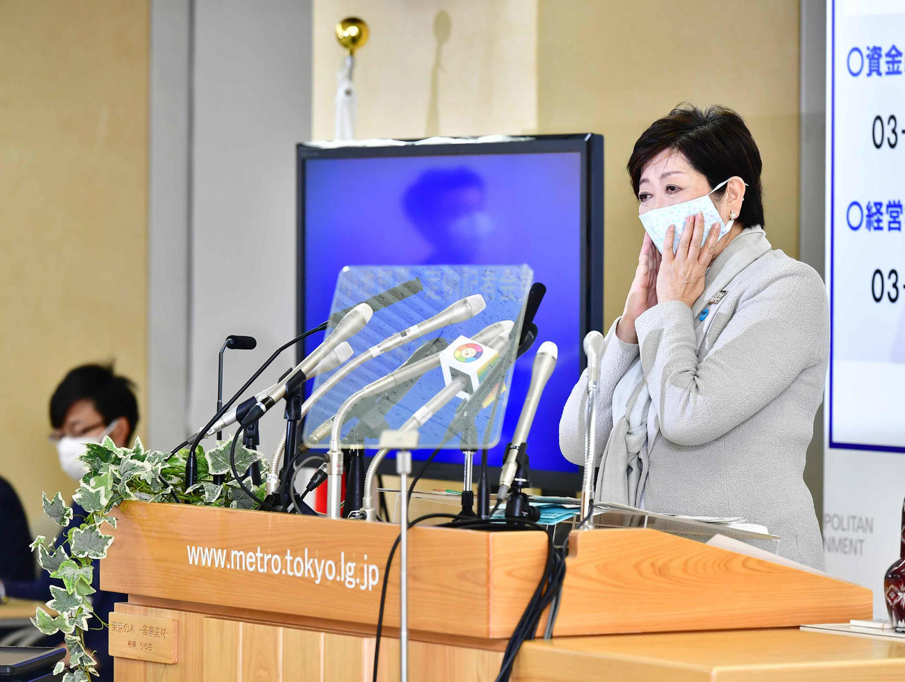 定例記者会見に臨みマスクを手で押さえながら記者の質問に耳を傾ける小池百合子東京都知事（撮影・小沢裕）